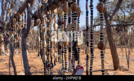 Nahaufnahme von Schnüren afrikanischer Halsketten aus Perlen und Samen, die auf einem Outdoor-Markt in Namibia ausgestellt werden. Hintergrund unscharf oder unscharf Stockfoto