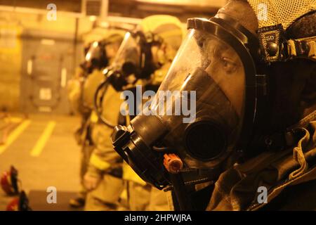 Die Schüler der Officer Candidate School (OCS) der Klasse 08-22 ziehen während der Feuerwehrausbildung beim Officer Training Command Newport (OTCN), Rhode Island, Februar 17, den eigenständigen Atemschutzapparat (SCBA) an. Die OCS entwickelt Zivilisten und Flottensegler moralisch, geistig und körperlich zu neu beauftragten Offizieren und verleiht ihnen höchste ideale an Ehre, Mut und Engagement, um Absolventen auf den Dienst in der Flotte als Marineoffiziere vorzubereiten. (USA Navy Foto von Candidate Officer Robert Butts) Stockfoto