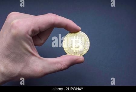 Mann Hand hält eine Bitcoin BTC Krypto Währung Goldmünze, neue virtuelle Geld-Konzept. Mining- oder Blockchain-Technologie Stockfoto