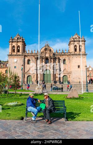 Zwei Männer sprechen auf einer Bank vor der Kathedrale von Cusco, Plaza de Armas, Cusco, Peru Stockfoto