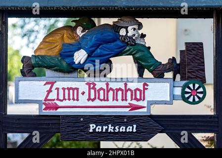 Geschnitzter Holzschild, zwei Männer eilen zum Bahnhof, Bad Salzhausen, Nidda, Wetteraukreis, Hessen, Deutschland Stockfoto