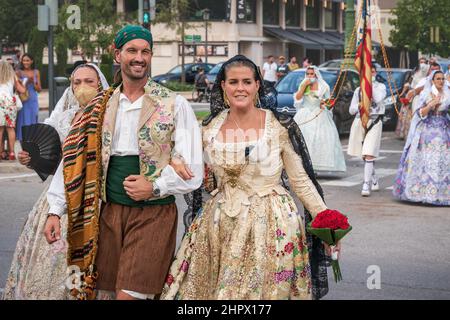 Valencia, Spanien - 4. September 2021: Paar geht mit traditioneller Blumenbekleidung zum Blumenangebot bei der Feier 'Fallas' Stockfoto