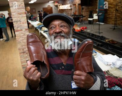 Marietta, Georgia, USA. 13th. Februar 2022. Ein Obdachloser zeigt seine Freude, ein Paar Schuhe von Tischen mit gespendeter Kleidung in der First Baptist Church in Marietta, Georgien, zu finden, während eines Abendessens für Einzelpersonen oder Familien, die finanziell oder obdachlos sind. (Bild: © Robin Rayne/ZUMA Press Wire) Stockfoto