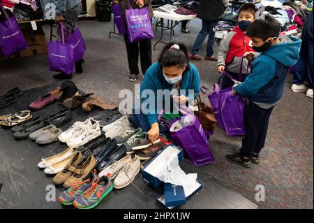 Marietta, Georgia, USA. 13th. Februar 2022. Bei einem Abendessen für Einzelpersonen oder Familien, die finanziell kämpfen oder obdachlos sind, untersucht eine Mutter Schuhe für sich und ihre Kinder aus Stapel gespendeter Kleidung in der First Baptist Church in Marietta, Georgien. (Bild: © Robin Rayne/ZUMA Press Wire) Stockfoto