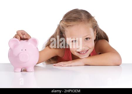 Sparen für ihre Zukunft. Aufnahme eines niedlichen jungen Mädchens mit einem Sparschwein. Stockfoto