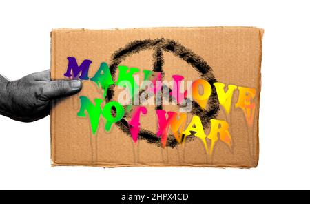 Ein Karton-Poster mit einer pazifistischen Legende auf weißem Hintergrund. Hand hält das Schild von der Seite. Stockfoto