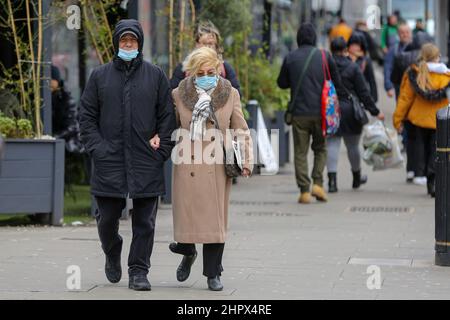 London, Großbritannien. 21st. Februar 2022. Ein Paar mit Gesichtsmasken als vorbeugende Maßnahme gegen die Ausbreitung des Coronavirus geht auf der Straße in London. Ab dem 24. Februar wird es in England nicht mehr gesetzlich vorgeschrieben, eine Gesichtsmaske zu tragen. (Foto: Dinendra Haria/SOPA Images/Sipa USA) Quelle: SIPA USA/Alamy Live News Stockfoto