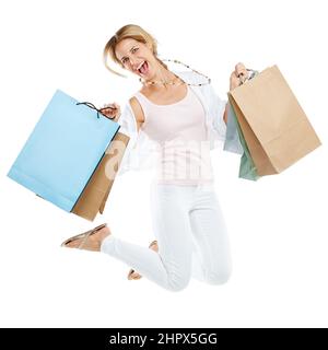 Shopping-Chaos in vollem Gange. Studioportrait einer aufgeregten jungen Frau, die Einkaufstaschen trägt und vor Freude vor weißem Hintergrund springt. Stockfoto