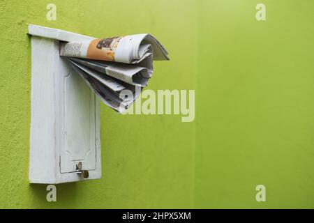 Das neueste Papier wird direkt in Ihre Mailbox geliefert. Ausgeschnittene Aufnahme von Zeitungen in einem Briefkasten. Stockfoto