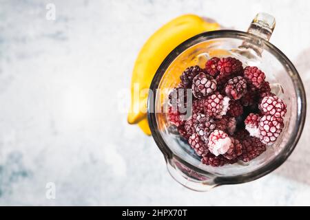 Gefrorene Himbeeren in einem Mixer, der bereit ist, ein gesunder Smoothie zu werden Stockfoto