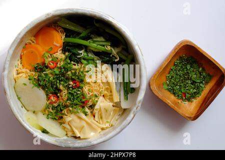 Vietnamesische vegane Mahlzeit zum schnellen Frühstück, Instant-Nudel-Koch mit Senfblatt, Karotte, Rübe, Tofu-Haut, Schüssel mit Nudelsuppe auf weißem Hintergrund Stockfoto