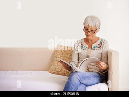 Ein paar friedliche Lektüre. Aufnahme einer älteren Frau, die ein Buch liest, während sie auf einem Sofa sitzt. Stockfoto