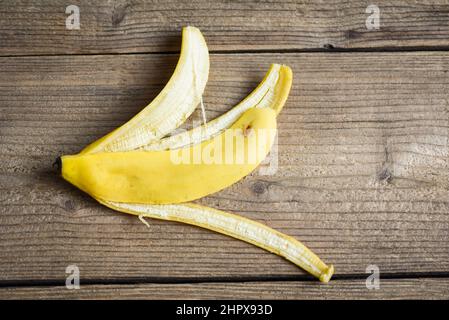 Bananenschale auf Holzhintergrund, reife Bananenschale auf dem Boden - Draufsicht Stockfoto