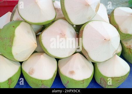 Haufen frischer junger Kokosnüsse, die in der Form geschnitten wurden, um zum Trinken geöffnet zu werden Stockfoto