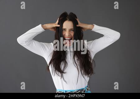 Schöne Brünette Frau schreit hält ihren Kopf Stockfoto