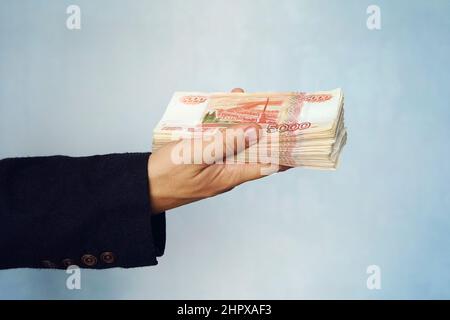 Ein Mann hält Rubel in der Hand, ein Geschäftsmann hält Geld in der Hand. Stockfoto