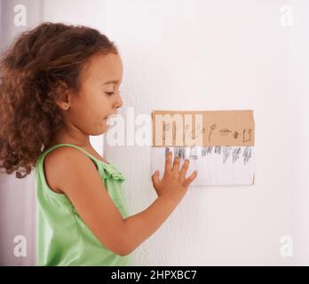 Spielen der Ebenholz und Elfenbein. Aufnahme eines entzückenden kleinen Mädchens, das mit einer handgezeichneten Klaviertastatur spielt. Stockfoto