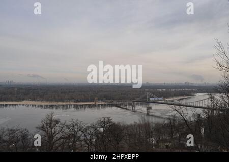 Blick nach Osten über den Dnjepr (Dnipro) von Kiew mit der Fußgängerbrücke (Parkowyi-Fußgängerbrücke) zur Trukhaniv-Insel auf der rechten Seite. Stockfoto