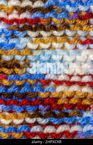 Hintergrund aus handgestricktem Garn mit abstrakter Vollformatstruktur in einer einfachen kraus Masche mit einem hellen, mehrfarbigen Muster Stockfoto