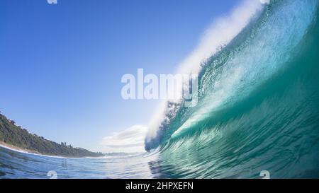 Das hohle Meerwasser der Ozeanwelle stürzt auf das flache Riff mit einer Nahaufnahme der Sonne, die im Licht der Natur schwimmt Stockfoto