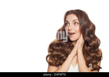 Porträt einer schönen, überraschten Frau mit langen, welligen Haaren isoliert. Rückansicht. Stockfoto