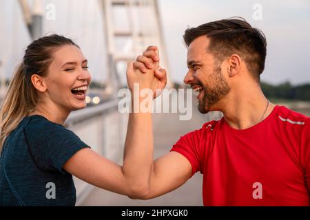 Workout am frühen Morgen. Glückliches Paar, das über die Brücke läuft. Ein gesunder Lebensstil. Stockfoto