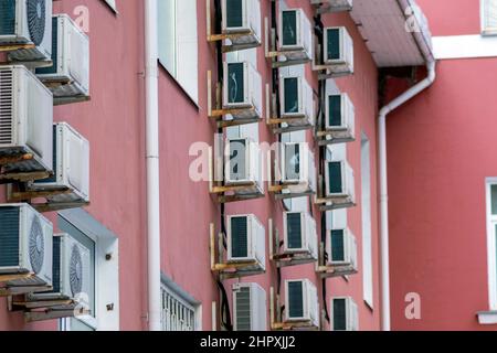 Klimaanlagen, die auf einem Gebäude montiert sind, das in violettem Außenbild gestrichen ist Stockfoto