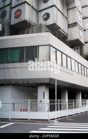 Basis des Nakagin Capsule Tower in Tokio mit einem Zaun um ihn herum. Stockfoto