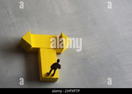 Entscheidungskonzept. Miniatur-Mann steht an einem Wendepunkt. Platz für Text kopieren. Stockfoto