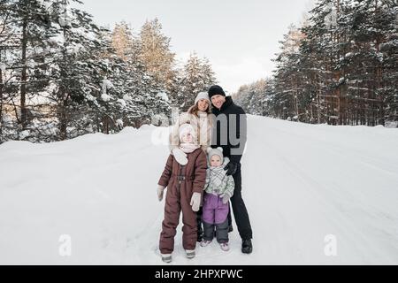 Vater, Mutter und zwei Töchter wandern durch den verschneiten Wald Stockfoto