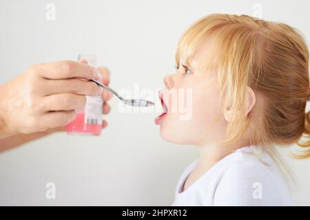 Shes ein wachsendes Mädchen. Ein niedliches Mädchen mit offenem Mund, das mit einem Löffel gefüttert werden kann. Stockfoto