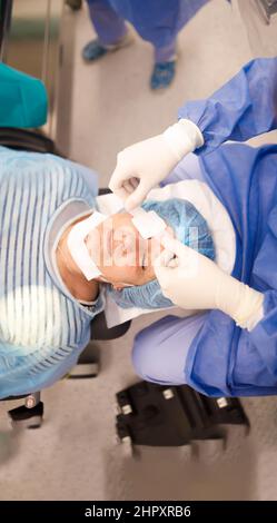 Arzt legt nach einer erfolgreichen Kataraktoperation einen Augenfleck auf seinen Patienten Stockfoto