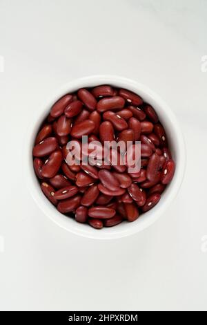 Schale mit roten Azuki-Bohnen auf weißem Marmorboden Stockfoto