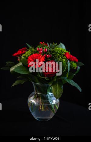 Roter Gerbera-Strauß in Glasvase, Stillleben, Low-Key-Bild Stockfoto