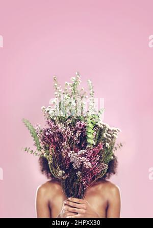 Wenn Sie gehen, um dann decken mit Schönheit. Studioaufnahme einer Frau, die ihr Gesicht mit einem Blumenstrauß bedeckt. Stockfoto