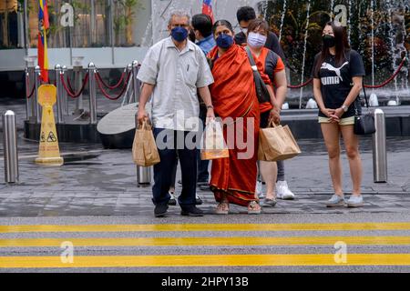 Kuala Lumpur, Malaysia. 24th. Februar 2022. Menschen mit Gesichtsmasken warten darauf, eine Straße in Kuala Lumpur, Malaysia, zu überqueren, 24. Februar 2022. Malaysia meldete am Mittwoch um Mitternacht 31.199 neue COVID-19-Infektionen mit der höchsten täglichen Spitzenmarke, was die nationale Gesamtzahl auf 3.305.157 beläuft, so das Gesundheitsministerium. Quelle: Chong Voon Chung/Xinhua/Alamy Live News Stockfoto