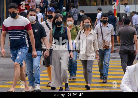 Kuala Lumpur, Malaysia. 24th. Februar 2022. Menschen mit Gesichtsmasken gehen in Kuala Lumpur, Malaysia, 24. Februar 2022, über eine Straße. Malaysia meldete am Mittwoch um Mitternacht 31.199 neue COVID-19-Infektionen mit der höchsten täglichen Spitzenmarke, was die nationale Gesamtzahl auf 3.305.157 beläuft, so das Gesundheitsministerium. Quelle: Chong Voon Chung/Xinhua/Alamy Live News Stockfoto