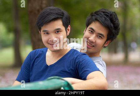 Genießen Sie die Freiheit, sich selbst zu sein. Niedlich junge Gay asiatische Paar lächelt zusammen, während im Park sitzen. Stockfoto