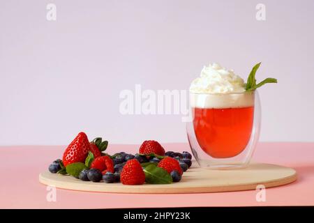 Pink Dessert – zum Frühstück Gelee mit Schlagsahne, dekoriert mit frischen Erdbeeren, Himbeeren und Blaubeeren Stockfoto