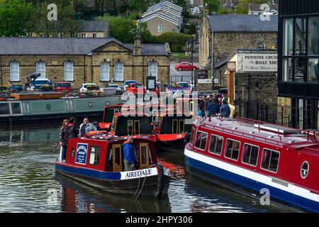 Urlaub Spaß Freizeitreise auf dem Wasser (Männer Frauen, Red Hire boat traveling, geschäftigen Marina Anlegestellen) - malerische Leeds-Liverpool Canal, Yorkshire, England, Großbritannien. Stockfoto