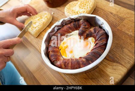 Ein skurriles Valentinstag-Frühstück mit herzförmigen Schweinen in Decken oder Wurst und Speck mit Spiegeleiern mit gebutterten Krümeln Stockfoto
