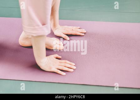 Hände und Beine einer Frau, die Yoga auf einer Yogamatte macht. sefl-Pflegerituale, Meditation und psychische Gesundheit, Ruhe und Entspannung, Seitenansicht. Stockfoto