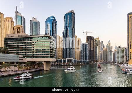 Yachten und Boote, die in der Dubai Marina kreuzen, umgeben von zahlreichen Wolkenkratzern, Restaurants, Geschäften und Hotels. VAE Stockfoto