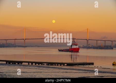 Morgendämmerung und Moonset über der Dartford-Brücke an einem kalten Wintermorgen mit Schlepper im Vordergrund Stockfoto