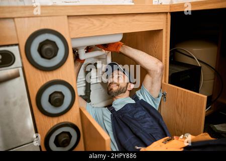 Fröhliche Klempner Befestigung Spülbecken Rohr in der Küche Stockfoto
