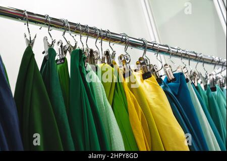 An der Theke hängen Muster von grün-gelben und blauen Stoffen Stockfoto