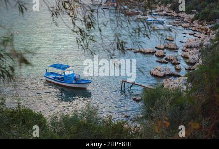 Kleine Fischerboote bei Sonnenuntergang - Kas Türkei. Boote und Berge an der türkischen Mittelmeerküste, beliebtes Touristenziel Stockfoto