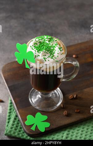 Irischer Kaffee in grüner Tasse und spezielle Cupcakes für den St. Patricks Day auf grünem Hintergrund. Alles gute zum St. Patricks Day. Stockfoto