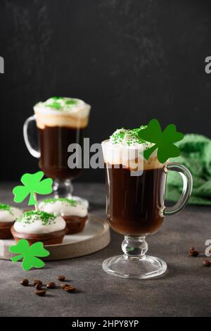 Irischer Kaffee in grüner Tasse und spezielle Cupcakes für den St. Patricks Day auf grünem Hintergrund. Alles gute zum St. Patricks Day. Stockfoto