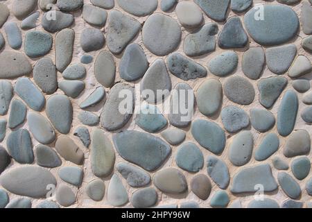 Zementwand mit kleinen, grauen und bläulichen Kieselsteinen. Ideal für den Hintergrund Stockfoto